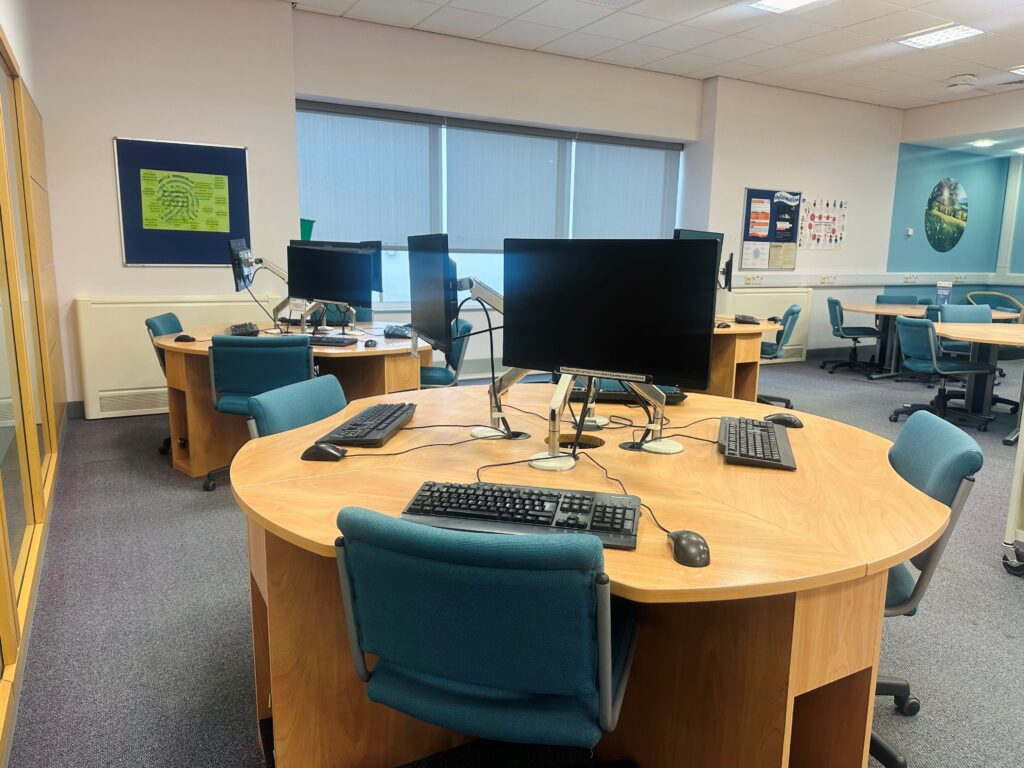 Image: Photo of open workspace at Redditch Health Library, shows tables and PCs. 