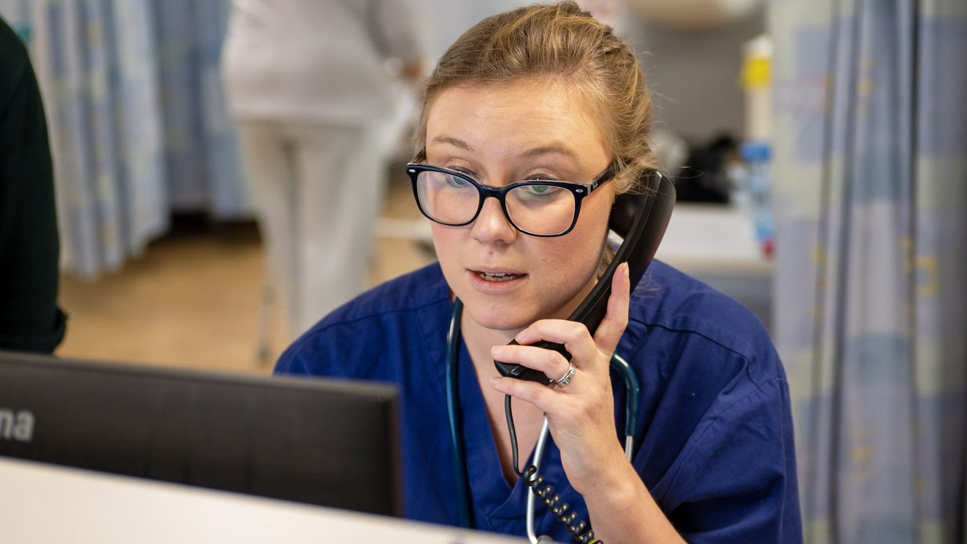 Photograph of a member of the hospital staff making a telephone call on a hospital ward.