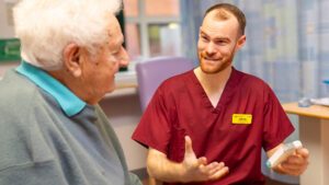 Pharmacist talking to patient about medication on ward.