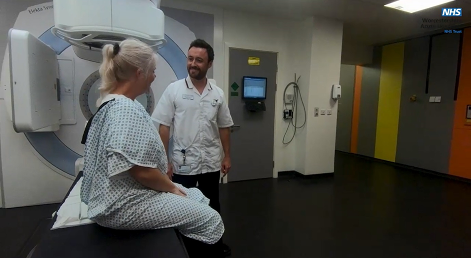 An image of a patient sat up on the bed after the scan has completed they are smiling and talking to the radiologist