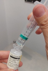 Vial of medicine with syringe in the top unbunged hole