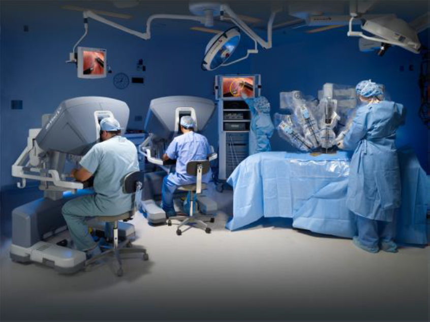 Surgeons operating robot in theatre