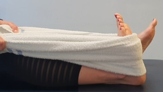 Foot being stretch toward body using a towel