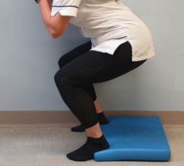 Squatting with heels raised on a mat or book