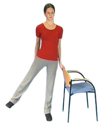 Person stood holding chair back raising leg to side