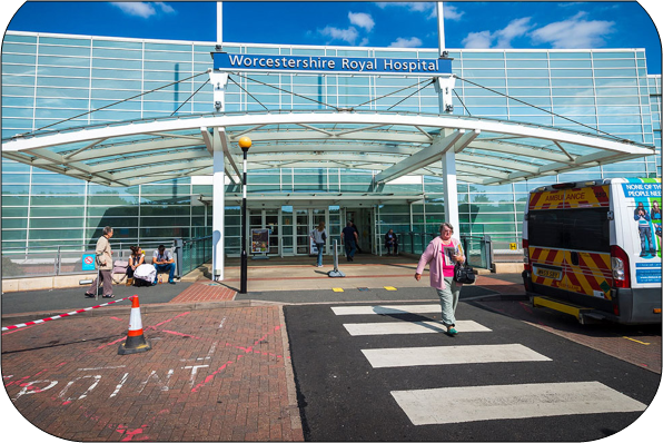 A photo of the main entrance to Worcester Royal Hospital a person is on a zebra crossing walking