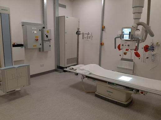 A photo of the x-ray room and the bed and equipment