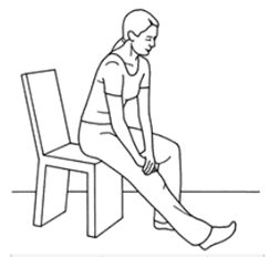 Person is sat on edge of a chair stretching leg out straight and using hands placed above knee to assist stretch