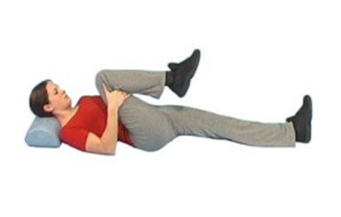 Image shows an individual lay on the ground, with head supported pulling a bent leg towards their chest
