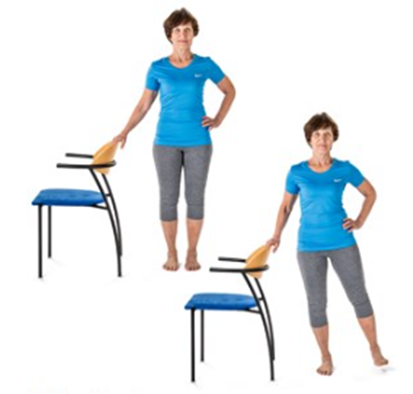 An image of an individual stood side on to a chair holding it for support and  raising the leg furthest from the chair out to the side a small way