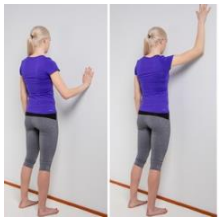 Image of person stood facing wall with palm on wall then sliding palm up along wall and back down to start point