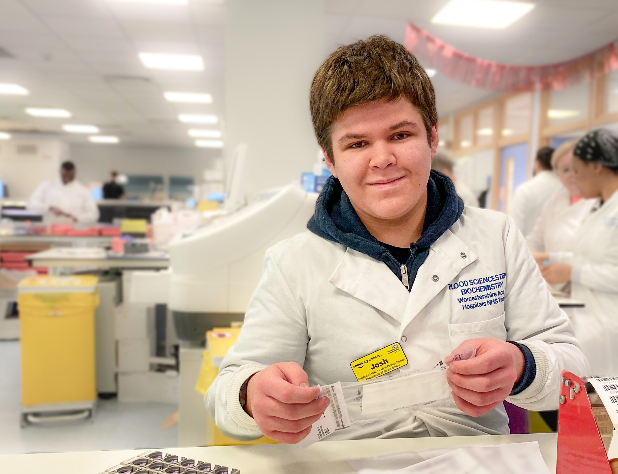 Photo of young man in laboratory smiling at camera.