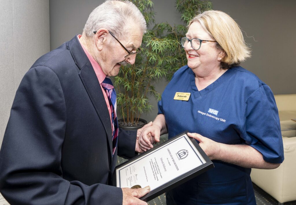 Fred Holland presenting Endoscopy Unit Manager, Deborah Hathaway with the team’s British Citizen Award certificate.