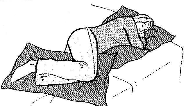 An individual lay on a bed on their side  head and waist supported by pillows and a pillow is placed between the knees 