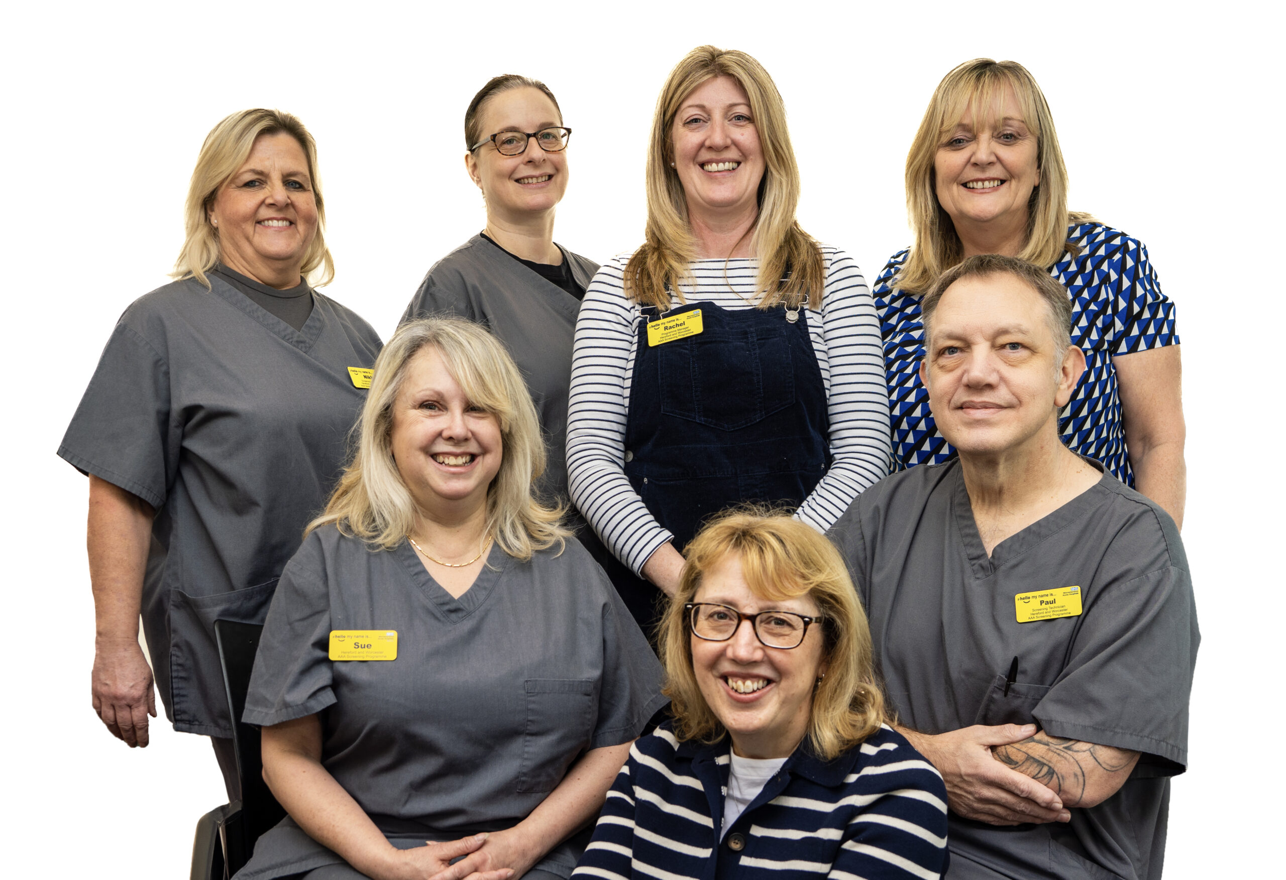 A team of 7 staff from the AAA team standing and sitting together, smiling at camera.