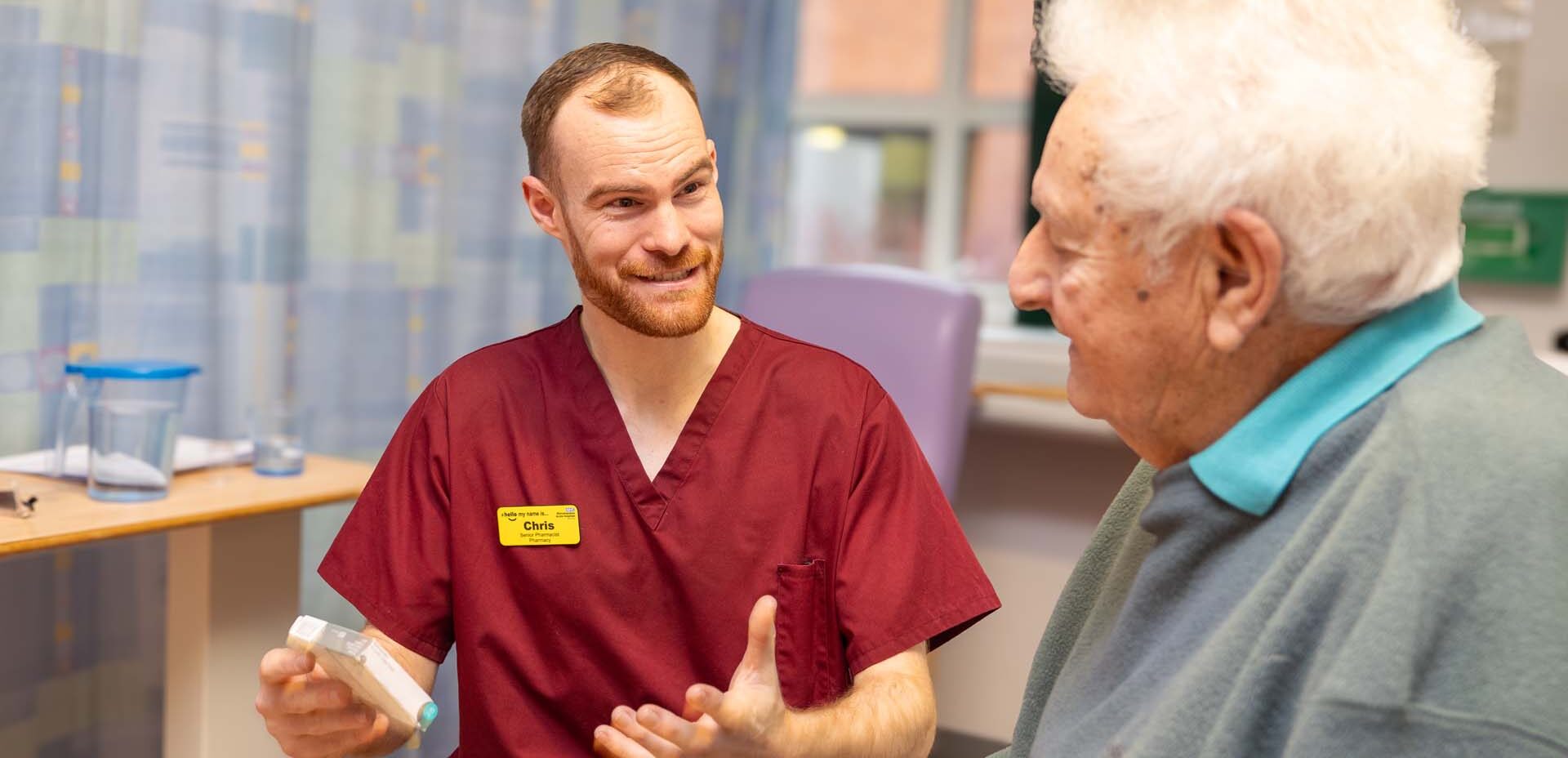 Photo of a pharmacist talking to a patient. In hands there is some medication.