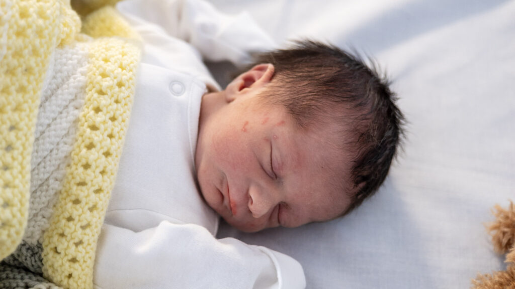 Newborn baby sleeping under blanket