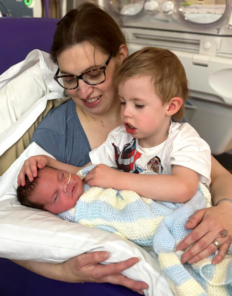 Helen (out of ICU) holding Maeve (off ventilation) alongside her son