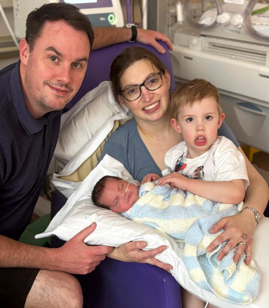 Helen (out of ICU) holding Maeve (off ventilation) and her son, alongside husband Justin