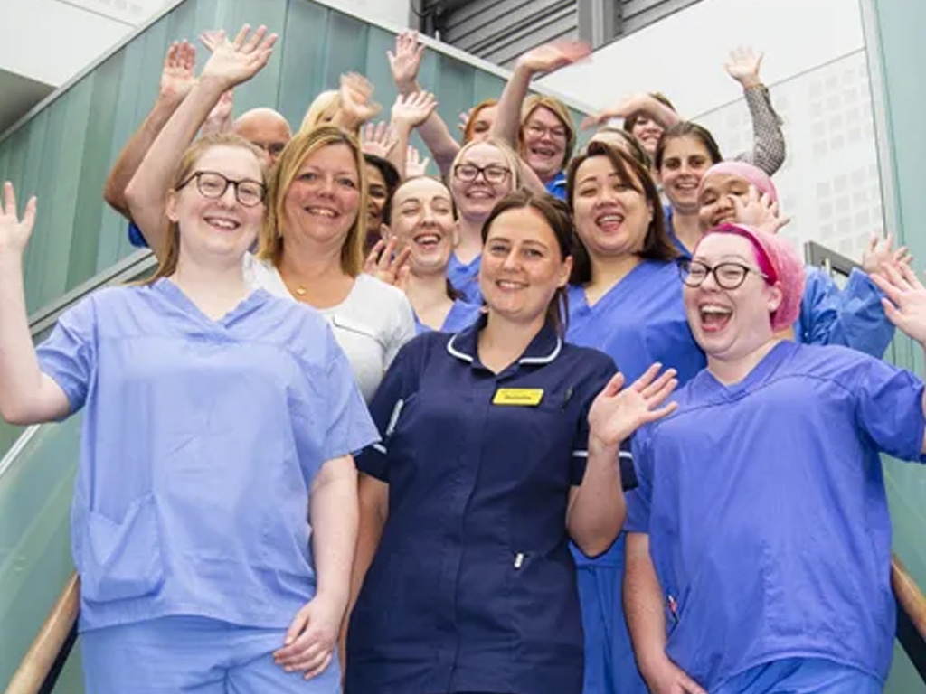 Photo showing happy smiling medical staff on stairs waving at camera.