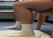 Image of person sat on a chair knees bent with feet in socks flat on floor one foot on a towel