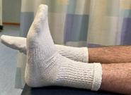 Lower legs flat on bed with one foot pointed up and the other toes pointed