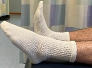 Lower legs flat on bed with one foot pointed up and the other toes pointed