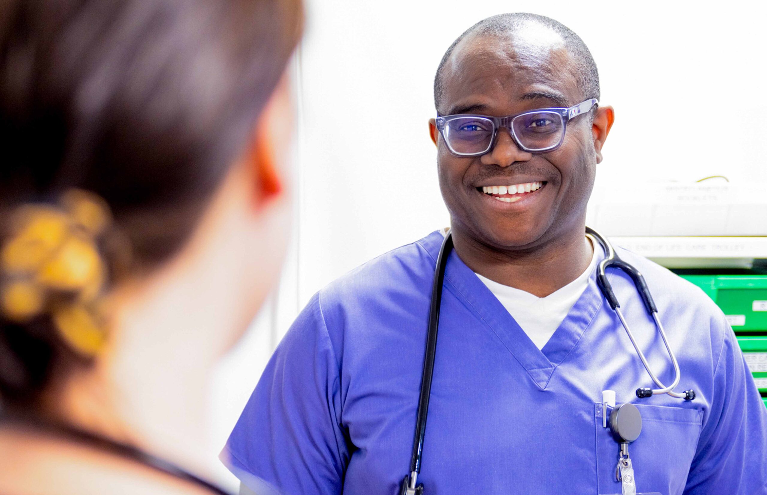 Photograph of a doctor smiling at a work colleague. Hospital background.