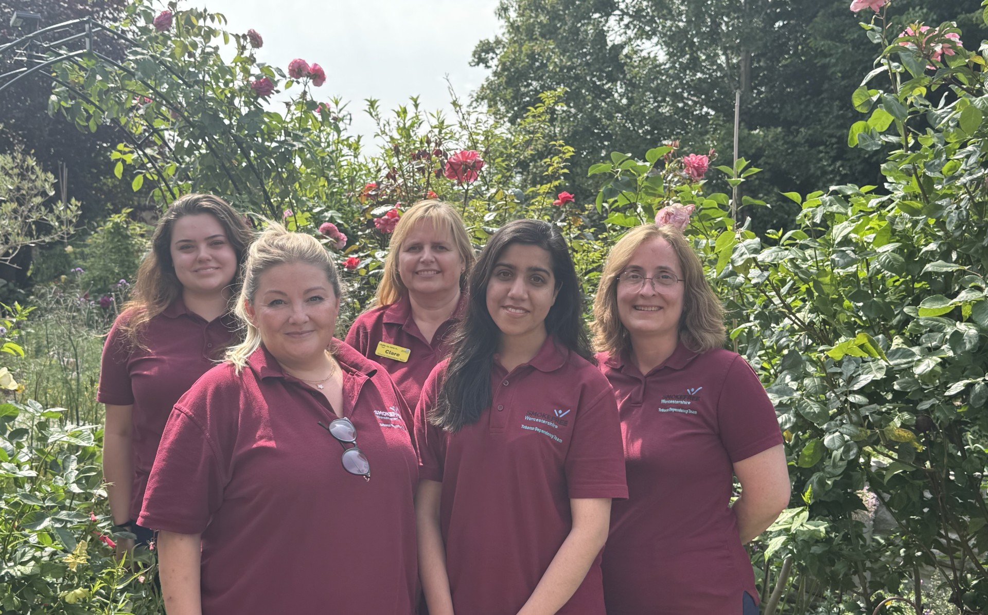 The Tobacco Dependency Prevention team stood together in uniform in a garden setting, smiling at camera.