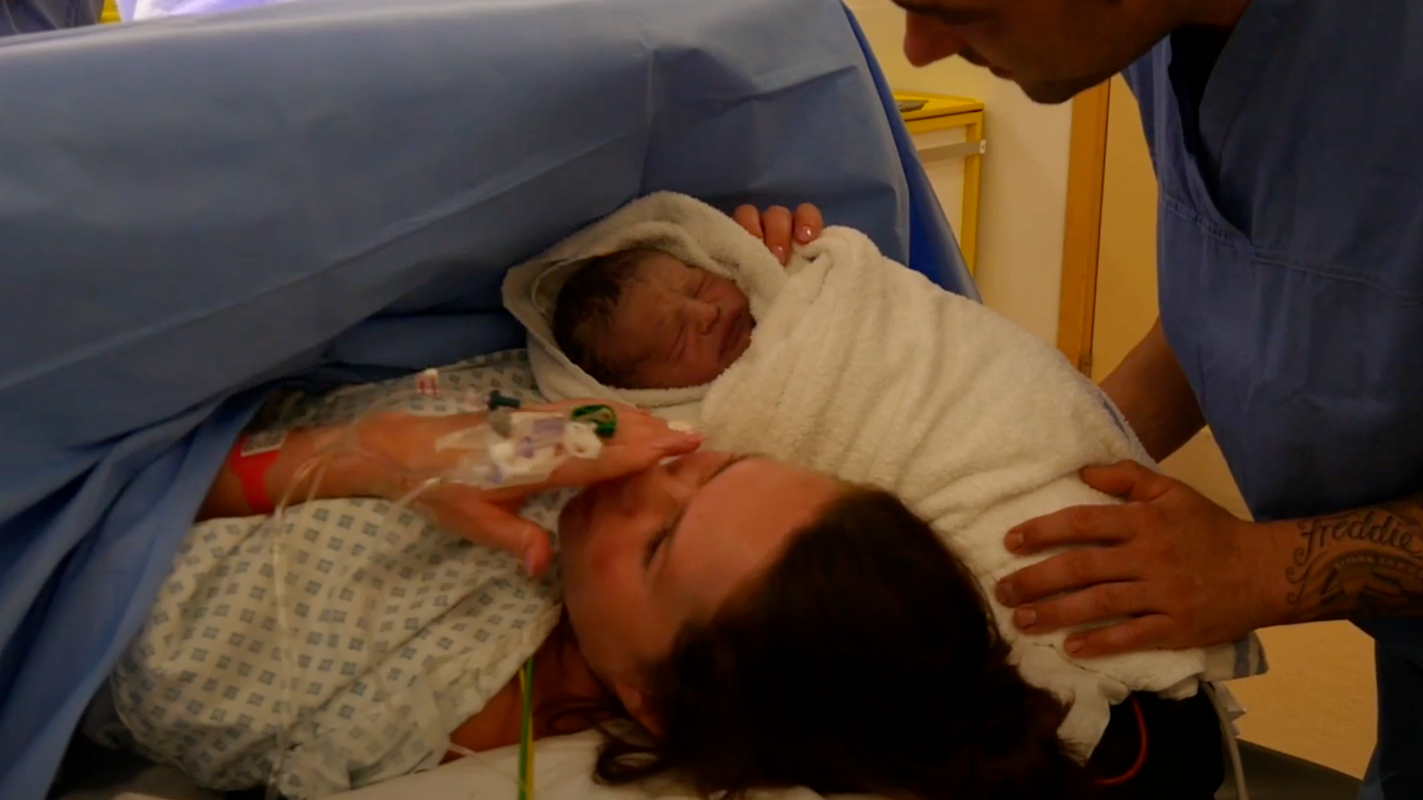 An operating theatre following a caesarean section with a new mother holding her newborn baby