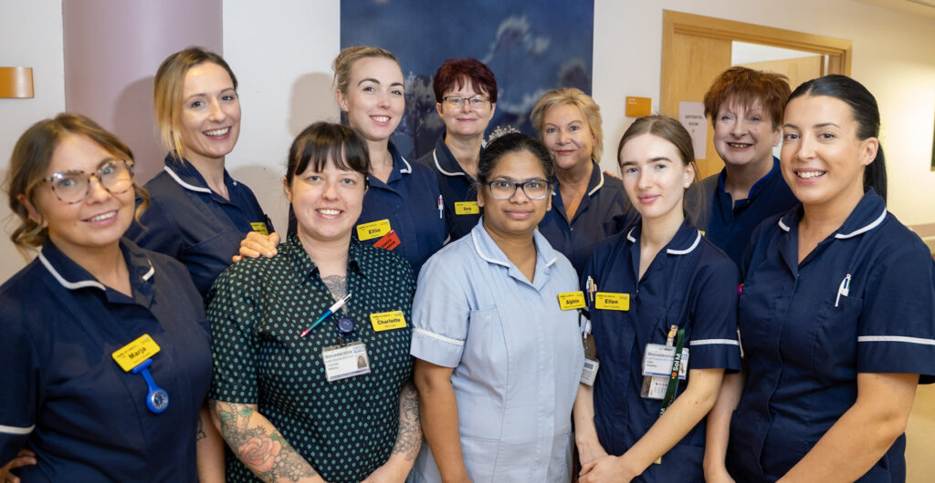 Antenatal ward team outside a room stood together smiling