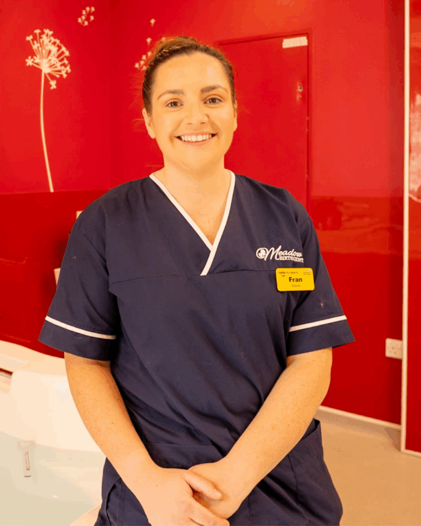 A midwife sat on the edge of a bathtub in a birthing suite.
