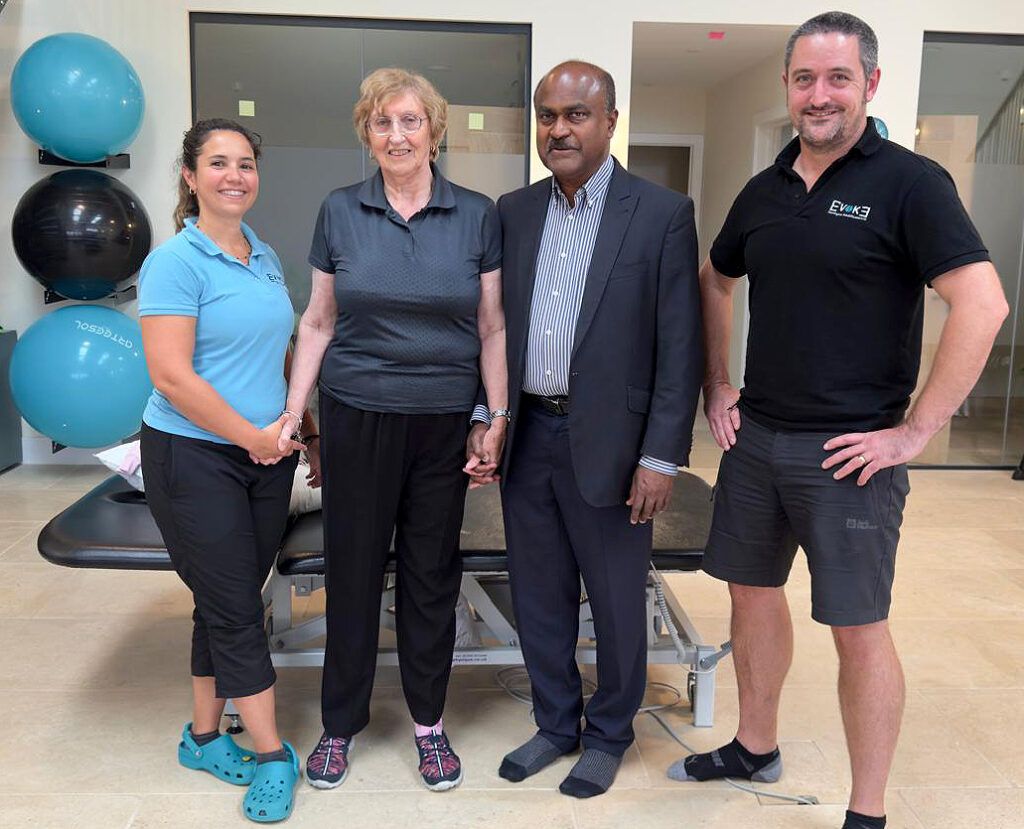 Sylvia stood up with Dr Shafeek and physios in the physiotherapy clinic.