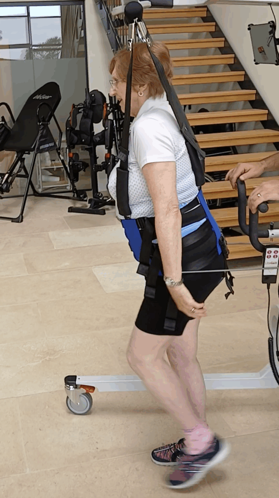 Sylvia walking during her specialised physiotherapy using a frame for balance