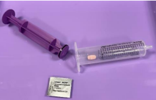 Syringe with plunger removed and pill placed in tube (also shows blister pack)