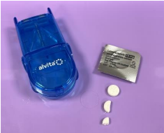 Tray with equipment to administer pills including the pills, blister pack and pil cutter. The pill is shown whole, halved and quartered