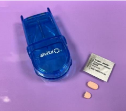 Tray with equipment to administer pills including the pills, blister pack and pil cutter, the pill is shown whole and halved