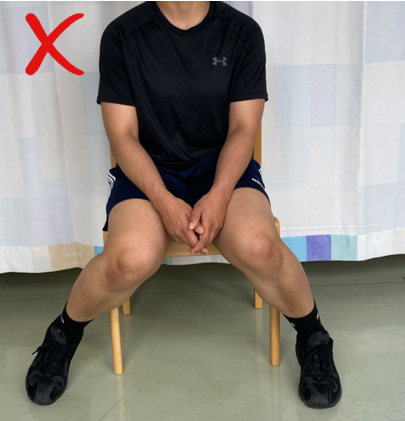 A do not image with a red cross of someone sat on a chair with legs splayed out at the knees