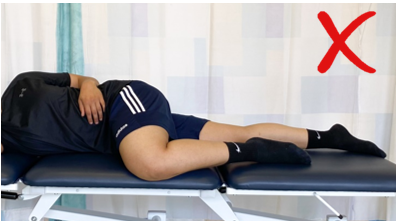 A do not image with a red cross showing an individual lay on side but  top knee is rolled onto bed in front of them 