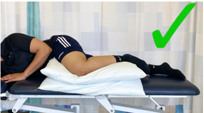 A do image with a green tick showing an individual lay on side with top knee supported by 2 pillows in front of them