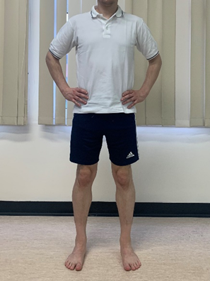 Image shows an individual stood with hands on hips and feet waist width apart
