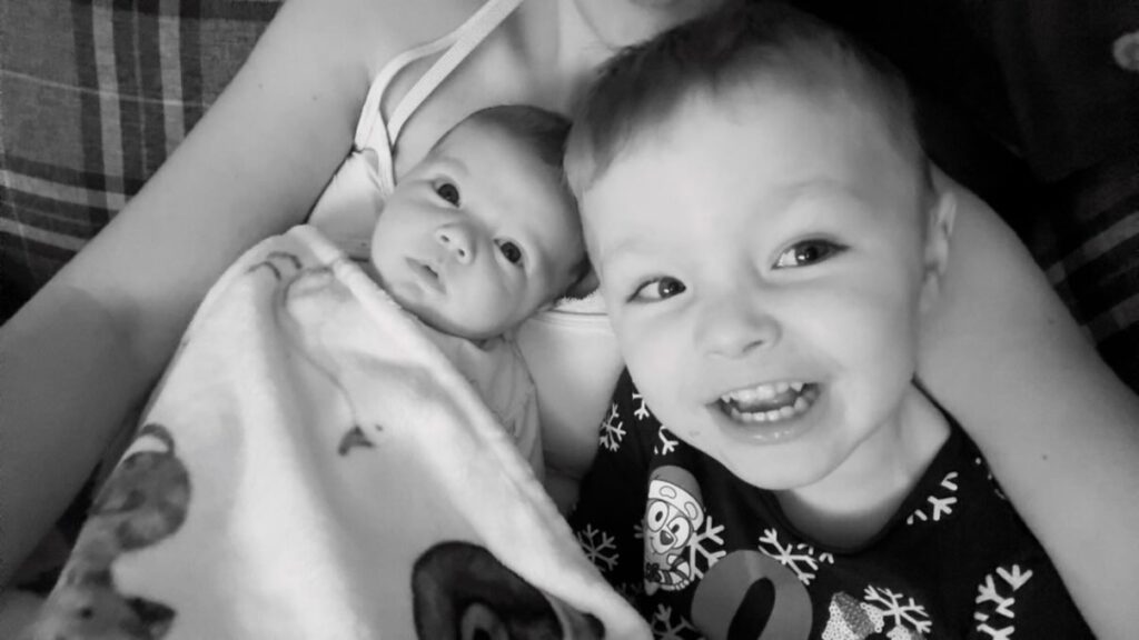 Thomas back home being held by his mother Zoe alongside his older brother.