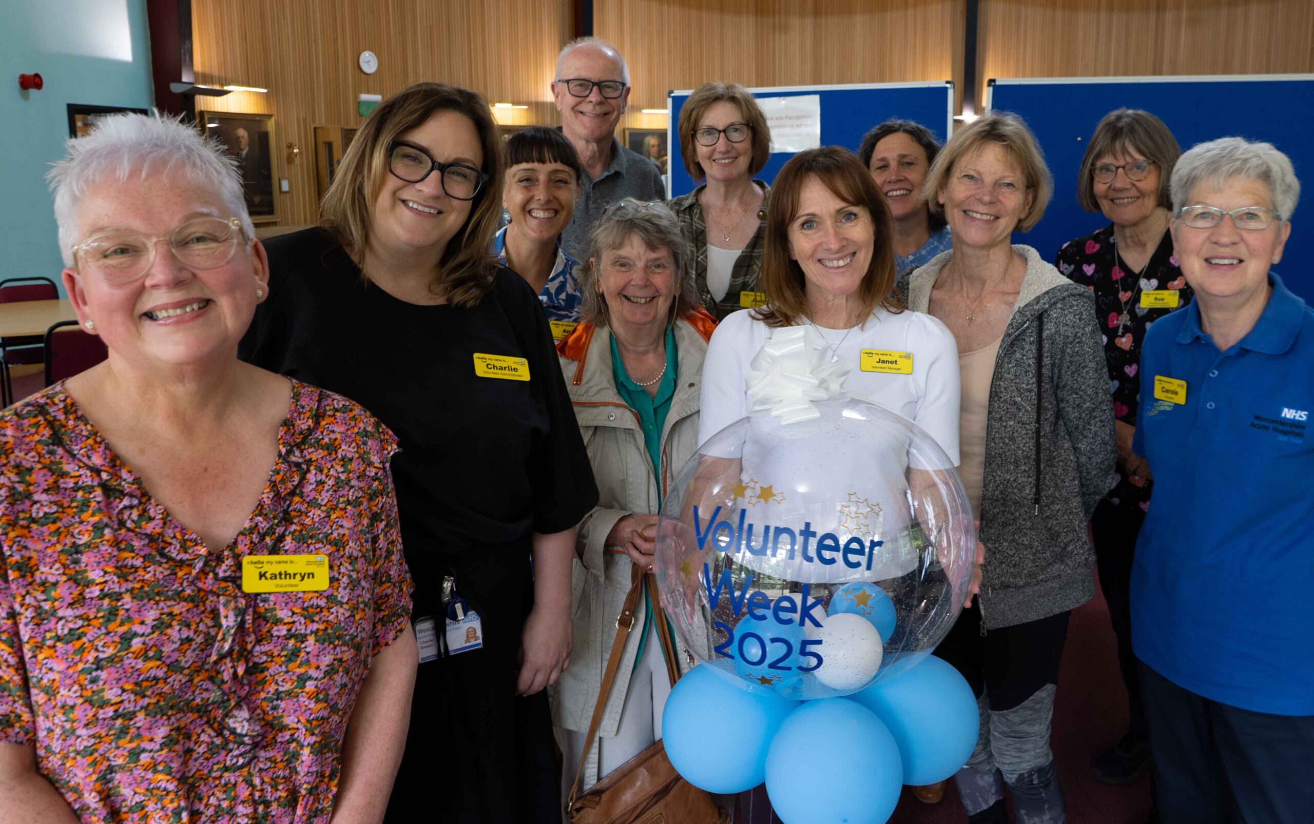 Photograph of a group of volunteers smiling with Volunteer Manager in centre. Celebrating Volunteer Week 2025.