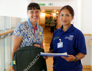 Davina with colleague standing in hospital corridor. Both looking at camera and smiling. 