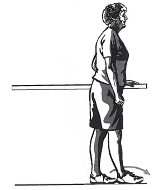 Picture of a person standing sideways next to a table, holding onto the surface with one hand whilst moving the foot in front of the other