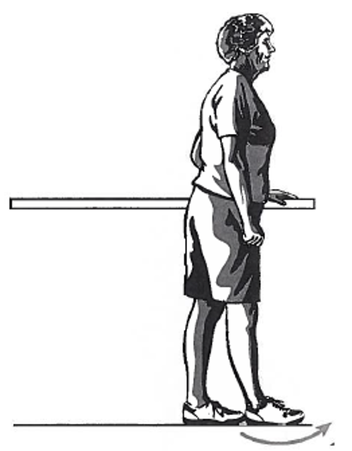 Picture of a person standing sideways next to a table, holding onto the surface with one hand whilst moving the foot in front of the other