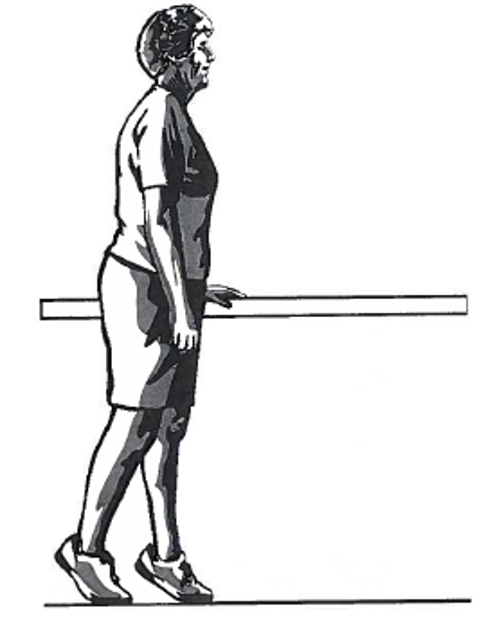 Picture of a person standing sideways next to a table, holding onto the surface with one hand whilst walking using toes