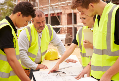 A picture of a group of people looking at housing plans at a building site