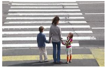A photograph of a group of people on the pavement next to a zebra crossing