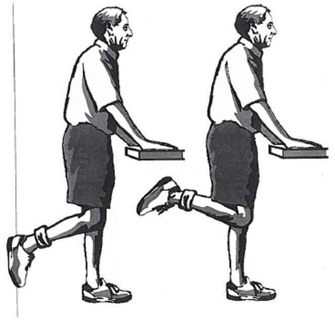 Picture of person using a table as support while raising one foot towards persons bottom